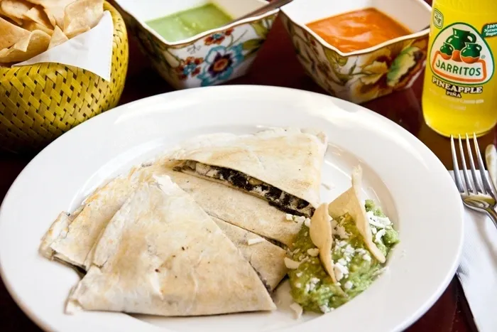 A plate of quesadillas and guacamole on a table.