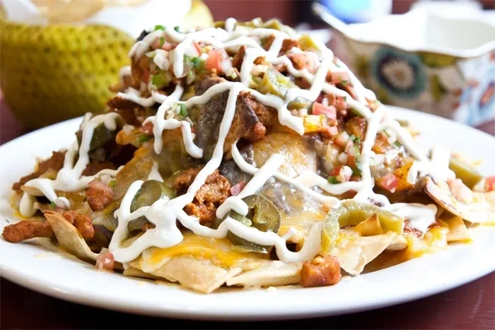 A plate of nachos topped with cheese and sauce.